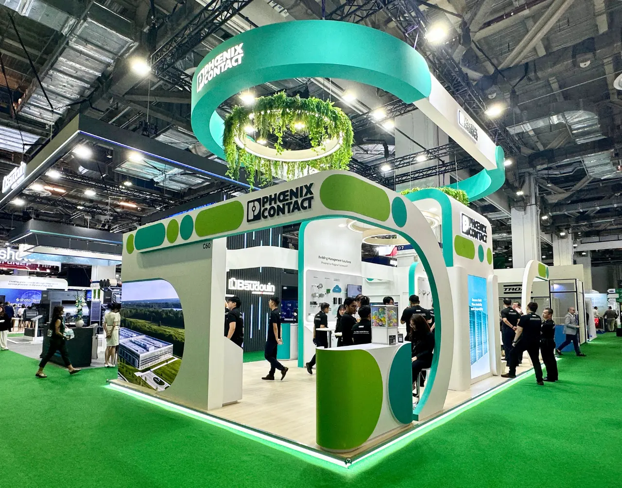 Green and white Phoenix Contact exhibition stand with circular suspended architecture and planting
