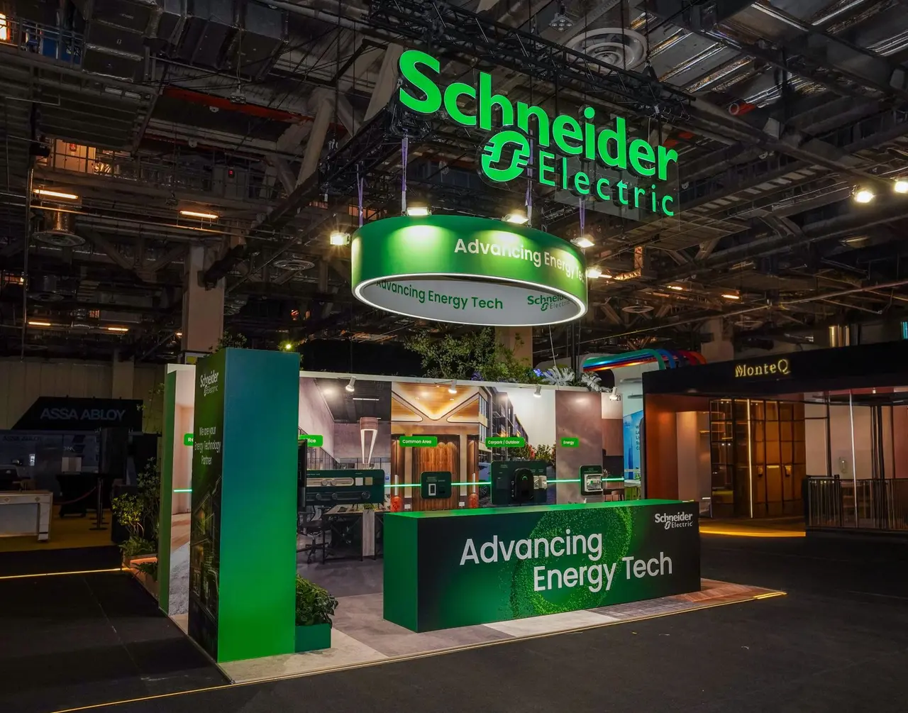 Green Schneider Electric exhibition stand with suspended illuminated branding, energy technology displays and planting